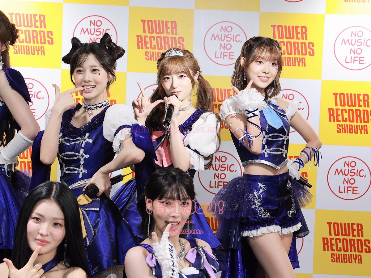 A group of young Japanese women in matching blue and white idol costumes pose at a Tower Records Shibuya event. The backdrop repeatedly displays 'TOWER RECORDS SHIBUYA' and 'NO MUSIC, NO LIFE.' with a watermark showing '15000円' and a URL.