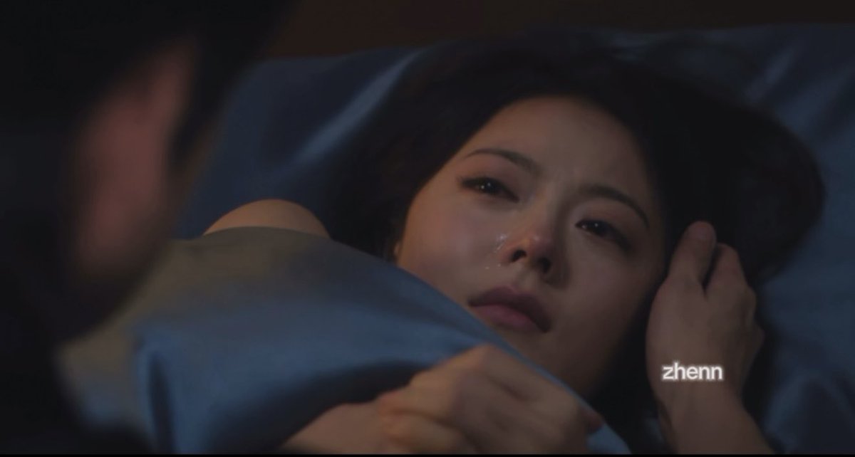 A scene from a drama showing an Asian woman lying in bed with a tearful expression, looking at a man whose face is out of frame, with the watermark 'zhenn' visible.