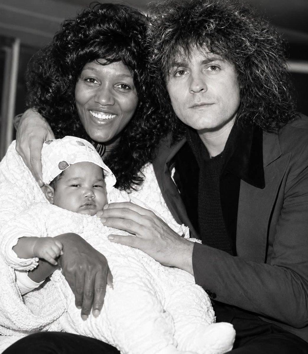 DOGEQEEN's tweet photo. She was not told that he had died until the day of his funeral.

Gloria Jones, the original singer of “Tainted Love” and the Queen of Northern Soul, fell in love with Marc Bolan of T. Rex. Their son Rolan was born, and Bolan said becoming a father was the greatest thing that had ever happened to him.

On September 16, 1977, Gloria was driving their purple Mini when it hit a tree. Bolan wasn’t wearing a seatbelt and died at the scene. He was 29 years old — just 14 days from his 30th birthday.

Gloria survived with serious injuries and was in the hospital. She was not told Marc had died until the day of his funeral.

Bolan’s will had been written before Rolan was born, and he was still legally married to his first wife. Under the law, Gloria and Rolan received nothing — no royalties, no estate. Fans looted their home, and Gloria went from a millionaire lifestyle to near poverty.

David Bowie, Bolan’s close friend and Rolan’s godfather, set up a trust fund for the boy and quietly supported them financially for years. The help continued for 17 years with no publicity. When Bowie died, Rolan wrote: “Thank you for always being there. You were a true friend to my father and to me.”

The sycamore tree from the crash still stands, and fans still leave flowers there. Years later, Gloria and her son co-founded a school of music.

Gloria started singing in church when she was seven.

She never really stopped.