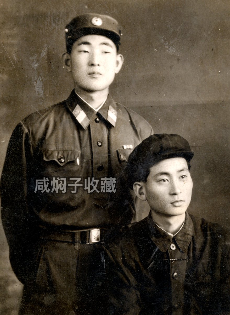 Samcheolli's tweet photo. 🇰🇵 Korean People's Army Staff Sergeant's Portrait w/ Friend (1970s)

Original undated studio portrait of an unnamed Staff Sergeant of the Korean People's Army with a friend or family member.

Based upon the uniform details such as the large cockade and lack of portrait badges, it is likely that this photo was taken in the 1970s. It is interesting to see that there is also a Military Merit Medal ribbon worn on the uniform.