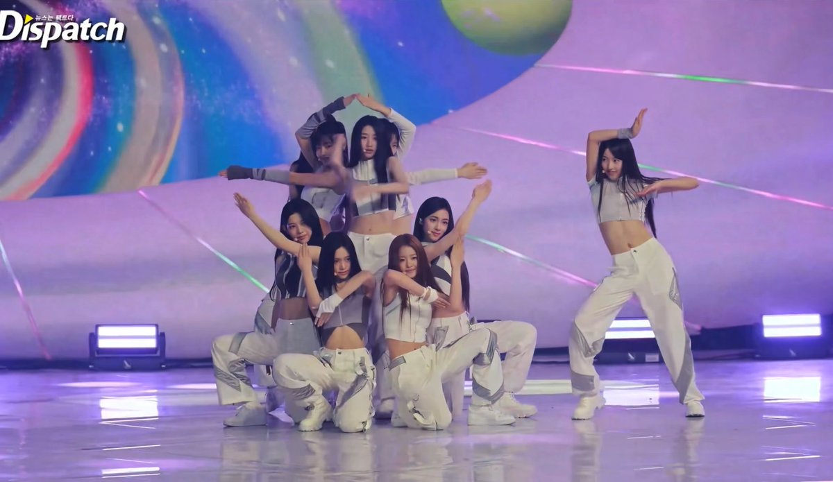 A K-pop girl group performs on stage in white outfits with a cosmic backdrop, with the 'Dispatch' watermark visible in the top left corner.