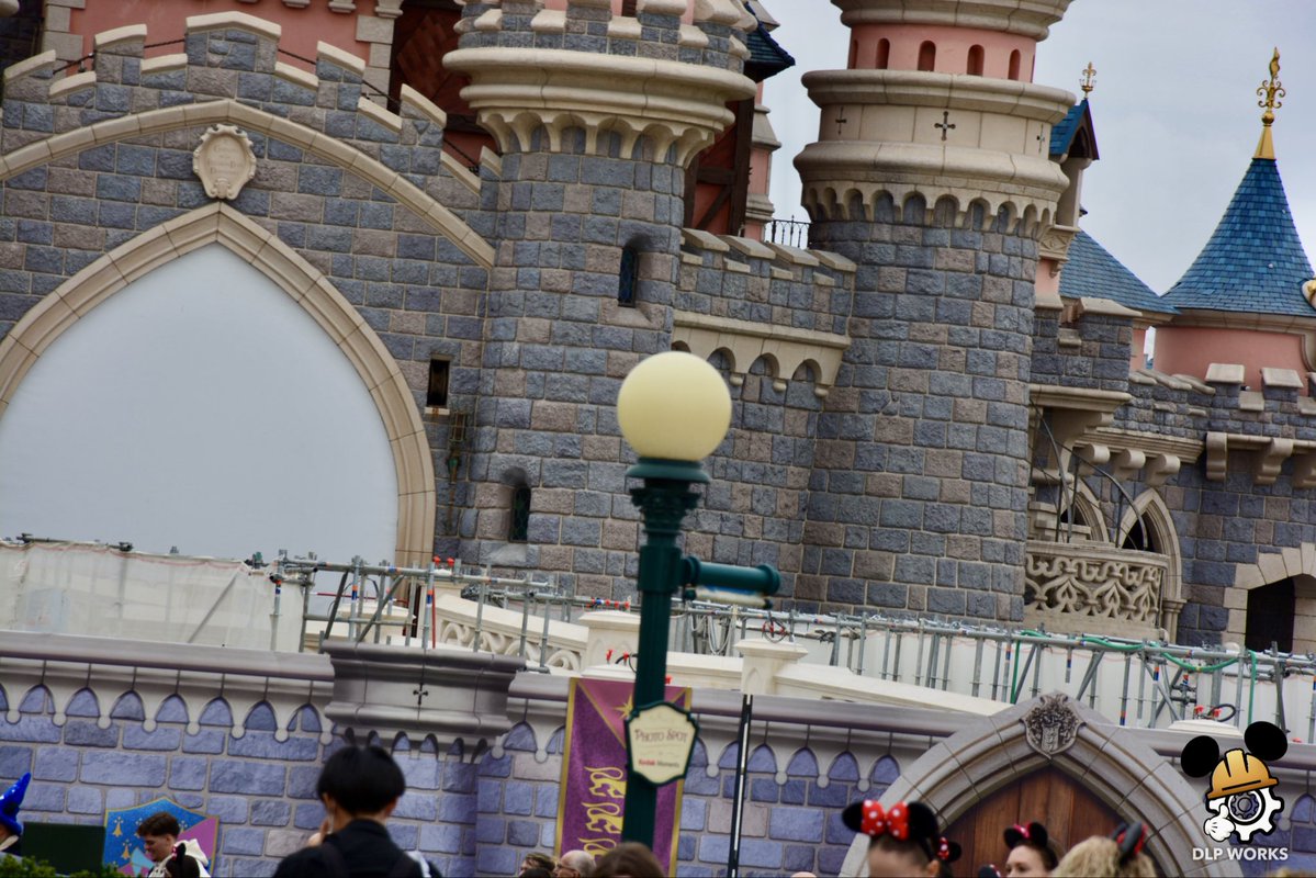 DLPWorks's tweet photo. [Live] ⚠️🚧 Themed tarps are being removed from the Castle Bridge!

➡️ Although the completion date officially announced by #DisneylandParis was September, the tarps surrounding the Castle Bridge are now being removed:
➖ The western section has already been uncovered, revealing part of the refurbished bridge!
➡️ On the bridge itself, the drawbridge chains & light fixtures still need to be reinstalled.
➡️ The project should be completed very soon, with the remaining tarps expected to be removed progressively. 
➖ Reopening is expected in the coming weeks!