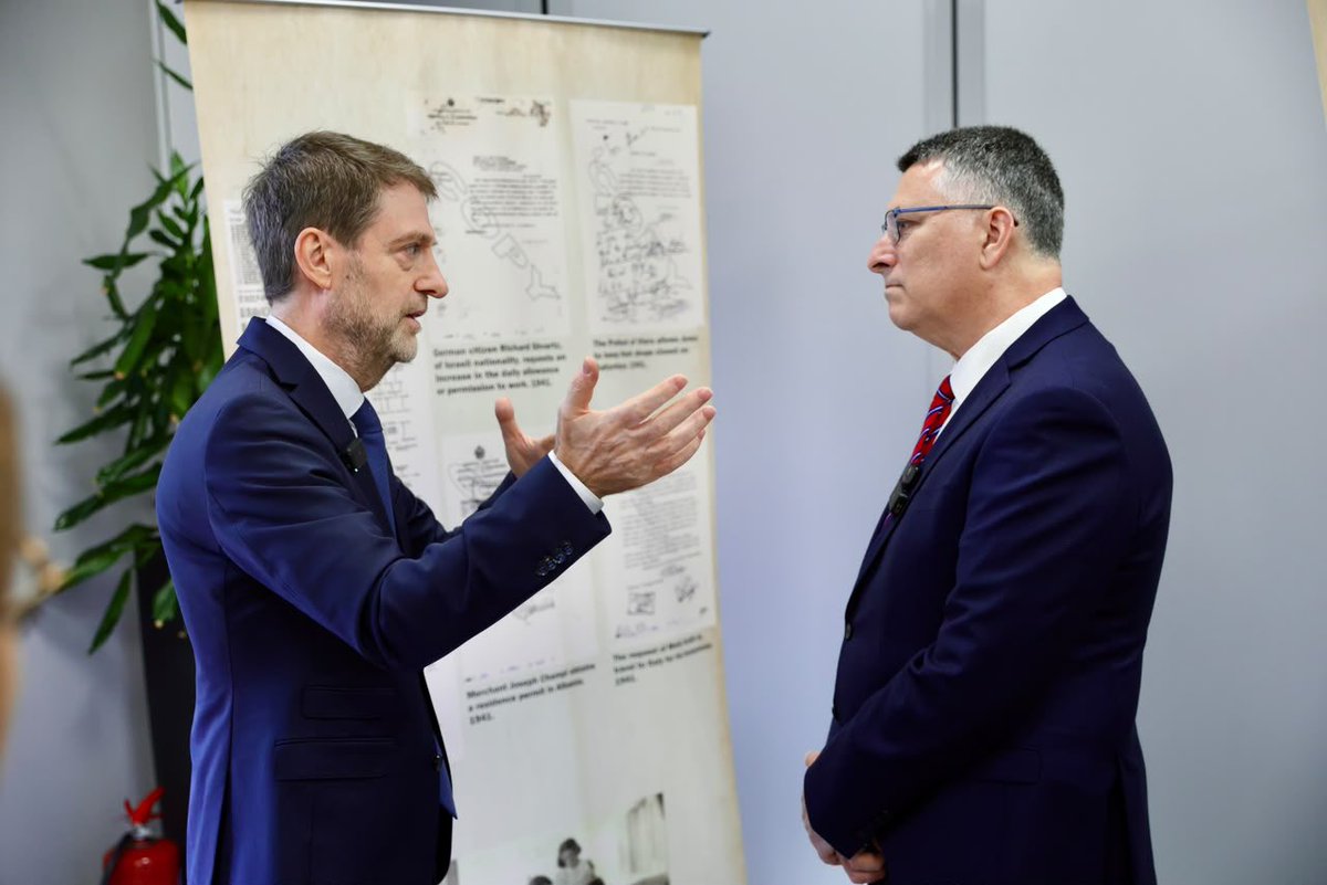 AlbanianDiplo's tweet photo. A passport was a path to safety; an open heart offered compassion; an open door provided protection and saved lives.

On the occasion of the visit of Israel’s Foreign Minister, Gideon Sa’ar, the Ministry for Europe and Foreign Affairs presented to the Israeli delegation a selection of historical and archival documents bearing witness to the extraordinary role played by Albanians in protecting and saving Jews during the Holocaust. 

The exhibition highlighted official correspondence, travel documents, and diplomatic records that tell a remarkable story of courage, solidarity, and humanity during one of history’s darkest chapters.
Ministers @HoxhaFer and @gidonsaar viewed archival documents recounting the efforts of Albanian officials and diplomats who assisted Jews fleeing Nazi persecution, both those living in Albania and many others who travelled there seeking refuge in a country that had become known as a sanctuary for Jews. 

Behind every passport, visa, official letter, and carefully crafted disguise stood a human life and the hope of survival.
The Ministers also visited the “Tree of Remembrance”, planted on Holocaust Remembrance Day as a symbol of memory, responsibility, and friendship. 

The olive tree carries messages from students of Tirana’s Sami Frashëri High School and Berlin’s Refik Veseli School.

From the courageous actions of those who, guided by BESA, the Albanian code of honnor, chose humanity over indifference and courage over fear, to the young people who keep their memory alive today, this legacy continues to resonate across borders and generations. 

It remains a powerful foundation of the enduring friendship and partnership between Albania and Israel. 🇦🇱🇮🇱