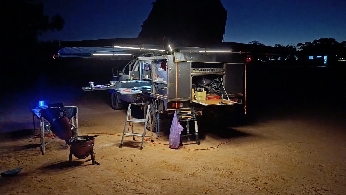 JesseRivet's tweet photo. Camp's up after dark, awning lights on, dinner on the coals.

Asked the awning how it copes with the wind out here. Reckons it just tries to stay grounded. 😂

Sand pegs that actually hold in soft red dirt, 10 for $30.95: https://t.co/LQsVTrZRwV

#DickinAroundInTheBush #CampLife https://t.co/iq5ZLVE2eq