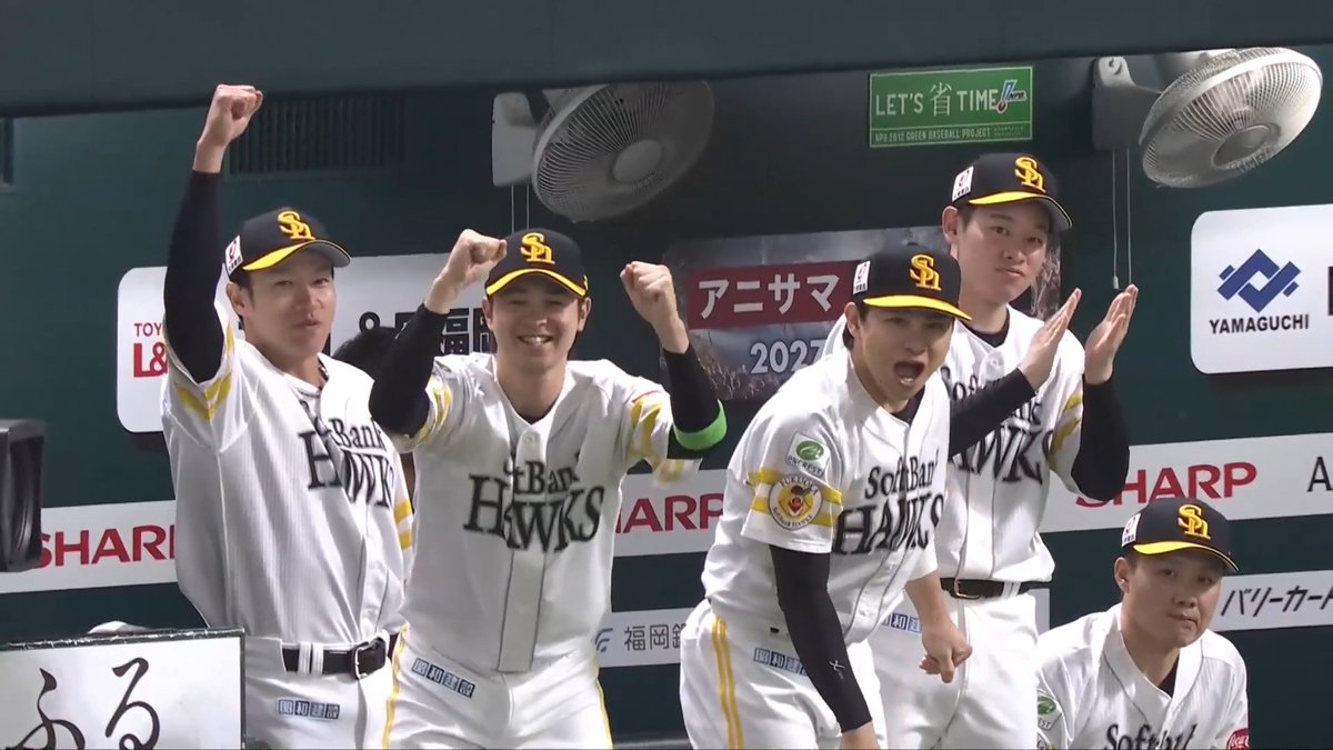 Members of the Fukuoka SoftBank Hawks baseball team in white uniforms celebrating in the dugout, with Japanese advertising visible in the background.