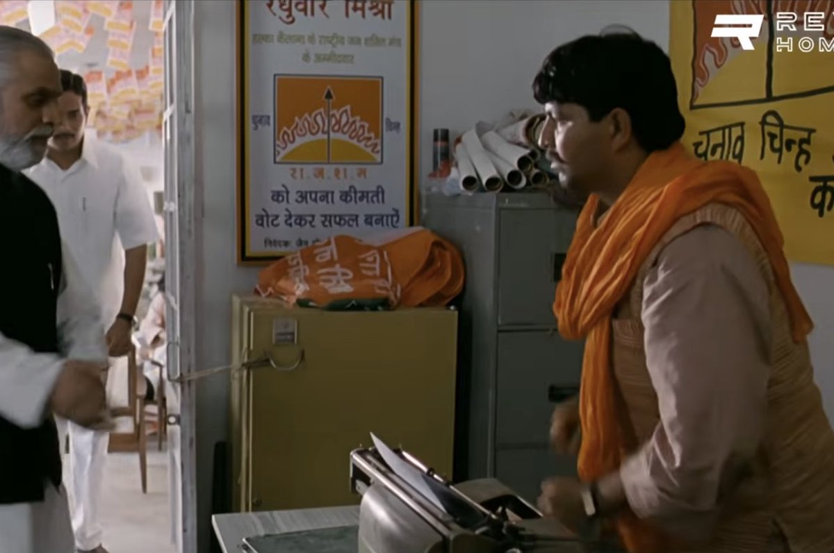 indusreunited's tweet photo. Propaganda in Rang De Basanti. 
It was actually the CONGRESS that was heavily involved in Mig 21 scams. 

Movies use various colours deliberately to drive association and emotion. The antagonist is draped in colours what is generally associated with the Indian Right Wing(ie not the Congress).  
> The colour of the gamchas, clothing  
> the colour of objects in the room(like a bag) 
> Interestingly, when one of the antagonist joins the documentary(even before the Mig 21 accident), they remove his orange tilak.   

When it was actually the Congress that was heavily involved in Mig 21, why portray these colours?