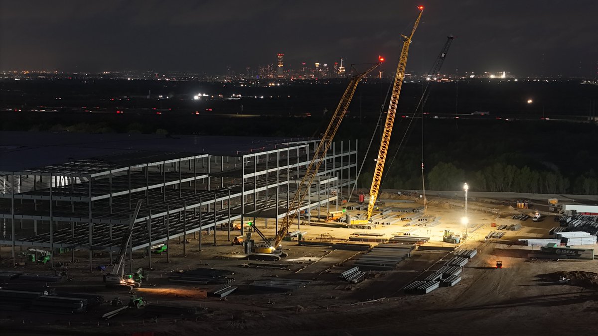 JoeTegtmeyer's tweet photo. The Optimus Factory at Giga Texas like you’ve never seen before! At night and all lit up showing off great views inside the structure that is now ~40% steel assembled! The main steel assembly may be complete by the end of the 1st Qtr in 2027, which would be truly amazing since that would be around 1 year after initial ground breaking began!

We can see the ground floor still has a lot of open trenches & part of the deep “plus” foundation footing pit still unfinished, along with some utilities work. The upper 3 floors show much has had concrete poured & even some sections os the roof as well ahead of the weatherproof membrane that will be installed once the roof is ready.

Take a look at the factory in a “new light’ today ! 😎🤖