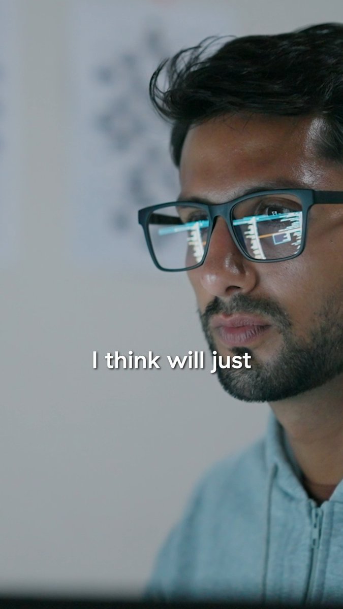 A close-up of a man wearing glasses, with computer code reflected in his lenses, accompanied by the subtitle 'I think will just'.