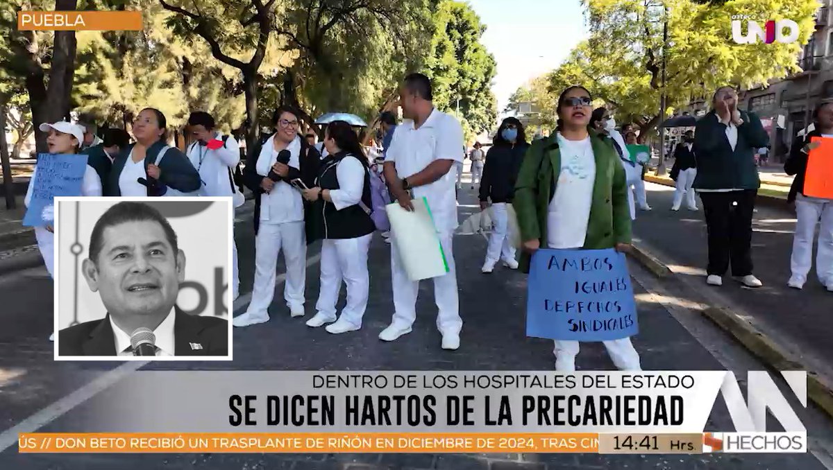 A news segment from N+ showing healthcare workers in white and green uniforms marching in protest in Puebla, with signs reading 'AMBOS IGUALES DERECHOS SINDICALES' and a headline stating 'DENTRO DE LOS HOSPITALES DEL ESTADO SE DICEN HARTOS DE LA PRECARIEDAD'.