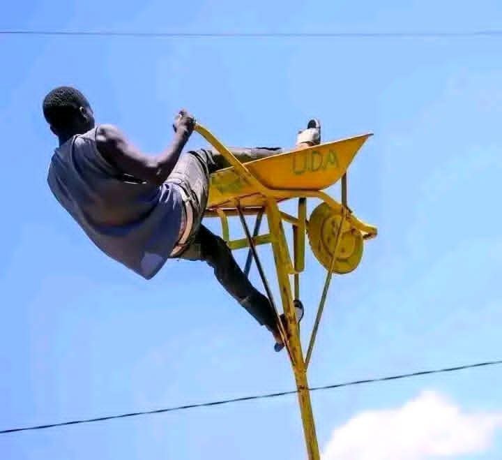 KipyegonNur's tweet photo. A man hanging on a wheelbarrow propped up high in the air as he tried to get a better view #2tam https://t.co/ffabylnRxK