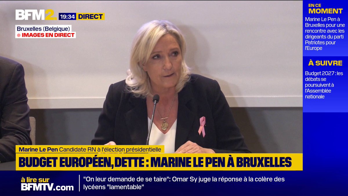 A BFM2 news broadcast at 19:34 showing Marine Le Pen, identified as 'Candidate RN à l'élection présidentielle,' at a meeting in Brussels with the headline 'BUDGET EUROPÉEN, DETTE : MARINE LE PEN À BRUXELLES.'