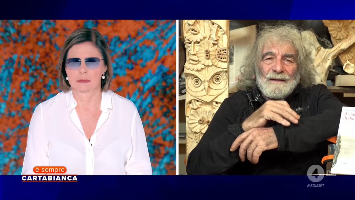 A split-screen from the Italian TV show 'è sempre CARTABIANCA' on MEDIASET shows a female host in sunglasses on the left and an older man with long white hair and beard on the right.