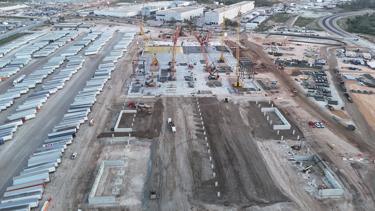 JoeTegtmeyer's tweet photo. On the E side of Giga Texas, the joint @SpaceX & @Tesla Advanced Tech Chip Fab foundation continues to receive huge concrete pours working to the N grade beam, while more footing & Footing support structures are completed on the S end. 

Steel erection on both the E & W sides of the center area is accelerating along with large steel truss structure assembly nearby, possibly to span the width of the foundation. This design ^ assembly is vastly different than any other structure on the site.

Large numbers of steel beams, many with welded on massive joining tabs have been delivered to the site while the nearby new concrete mobile batch plant is in operation to support construction of this $3B Research & Development facility.
