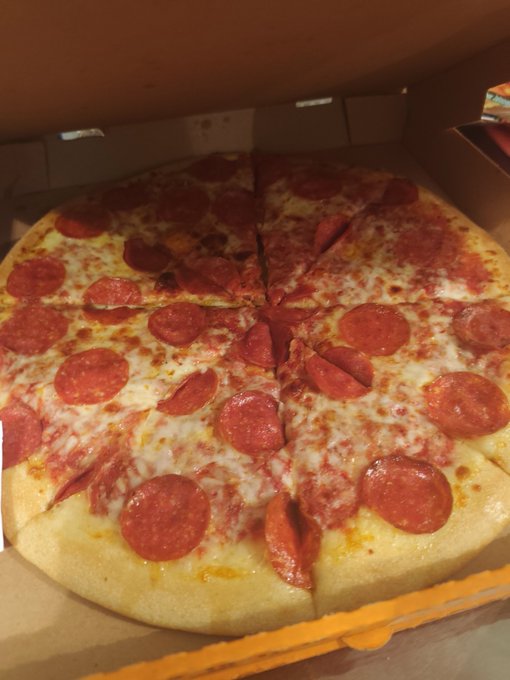 A pepperoni pizza with melted cheese sits in an open delivery box, cut into eight slices and ready to enjoy—perfectly fitting the "rate my eats" prompt as a tasty meal worth rating.