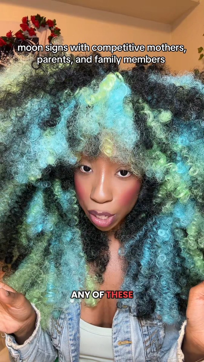 A woman with voluminous teal and green curly hair is shown with text overlay reading "moon signs with competitive mothers, parents, and family members" at the top and "ANY OF THESE" at the bottom.
