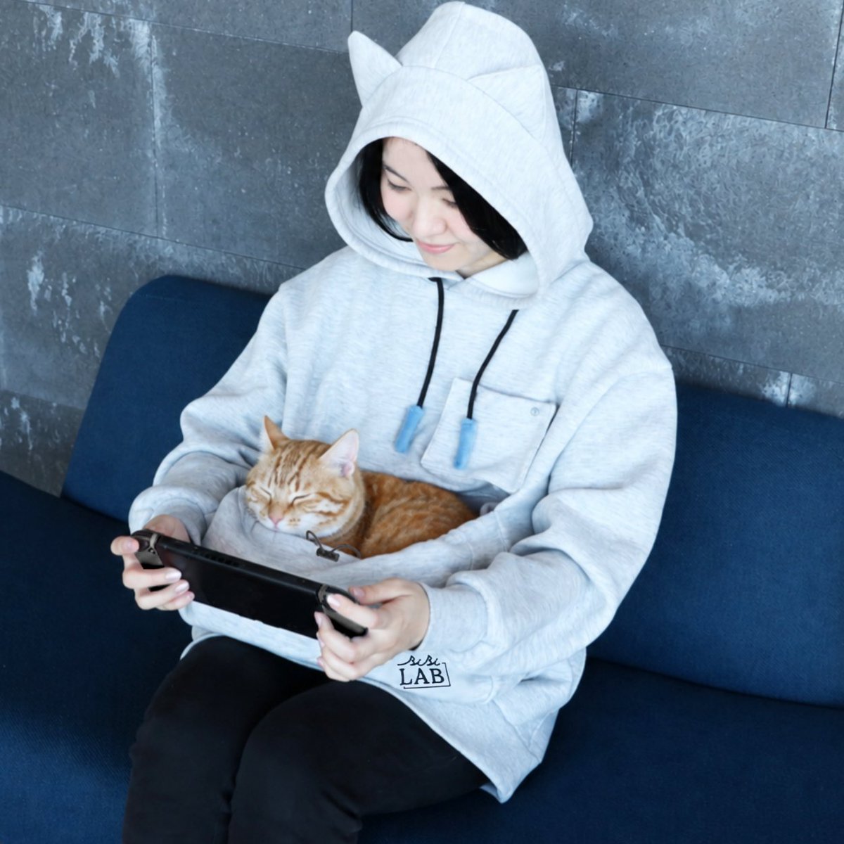 denfaminicogame's tweet photo. 愛猫を“お腹のポケット”にINできるルームウェア「にゃんガルーパーカー3」が発売。ゲーム中の“ネコハラ”を至福の時間に変える
https://t.co/4V7GKqFFc8

フードの紐の先端に「猫じゃらし」を備え、マッチング待ちや作業の合間にいつでも愛猫と遊べる。胸元に「猫撮りスマホポケット」も搭載 https://t.co/V1u94D3gUy
