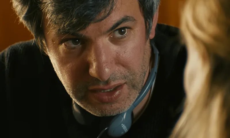 CinemaTweets1's tweet photo. Nathan Fielder is a genius. There’s no other way to put it. In what I believe to be the apex of Fielder’s career, You Can See Everything (🌟🌟🌟🌟🌟) is a masterpiece. Unquestionably deserving of The Five Star Treatment. But perhaps the single biggest compliment I can pay Fielder & this movie is that Fielder’s work goes beyond genre-defining: it’s genre-expanding. In other words, Fielder just changed my expectations of what it means to make a documentary. I don’t believe we’ve ever gotten a documentary like this before. As I sit here and write this review in disbelief, I question if we ever will again. The way co-directors Fielder and Lance Oppenheim create a journey that shoves you in the faces of two stone-cold sociopaths is a magic trick. This is a film that’s 3 hours long but somehow too short. I could’ve watched another 3 hours if you let me. Whatever Fielder is serving, I’m ordering. 
 The crux of the story here is straightforward yet mind-boggling; in 2023, before she was set to begin an 11 year long prison sentence, notorious Theranos founder and fraudster Elizabeth Holmes and her partner Billy Evans have invited Nathan Fielder to live with them and document her final days of freedom, encroaching on a family’s final moments together.  What follows is a documentary that blurs the line between truth and fiction with such force that it disappears all together. Every genuine moment might be a performance. Every conversation may have an ulterior motive. Every awkward silence could be strategic. And when the subject of Fielder’s documentary is no longer accessible to him, he continues his exploration and hunt for truth in the unique way that only Fielder knows how. 
 There is simply so much to unpack with this movie, because the conceit driving it all is an inherent oxymoron. How do you create a documentary, a piece of film designed to be transparent and truth-bearing, about people who are famous for being frauds? Who successfully lied and conned people who sit at the highest levels of government and industry? Can one document deception without participation? A documentary is inherently performative; everyone involved has a motive. That is dialed up to an 11 here, as Holmes and Evans are the quintessential final bosses of deceit and discomfort. You never know where you stand with either one. They are a two person cult. The second you start feeling bad for one, you wonder if you’re falling into their trap. No moral evaluation can be relied upon, because the audience’s perspective shifts constantly throughout the entire film. 
 Nathan Fielder was built in a lab for this movement. He is the perfect person for the job. He built a decades-long career in sitting back, allowing people to stew in their discomfort, and seeing what comes next. And to be totally honest, I think Holmes underestimated his intelligence. When a conversation reaches an awkward pause where a normal person would step in to fill the silence, Fielder lets it lie to see who chooses to fill it and with what. But here he may have met his match, in a couple that relies on prolonged eye contact, the guise of full access, and weaponized helplessness. One of the documentary’s great feats (of which there are many) is making us wonder if Fielder has gotten pulled too deep into their orbit. Fielder’s own biases may make him susceptible to the very manipulation he’s trying to expose. A great final moment between Fielder and his rehearsal scene partner brilliantly mimics and reverses the roles of his final conversation with Holmes before jail. Has the deceived become the deceiver….