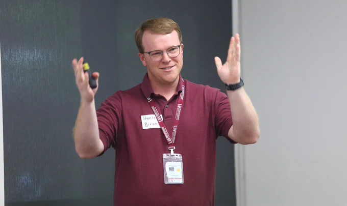 Man with glasses holding hands up