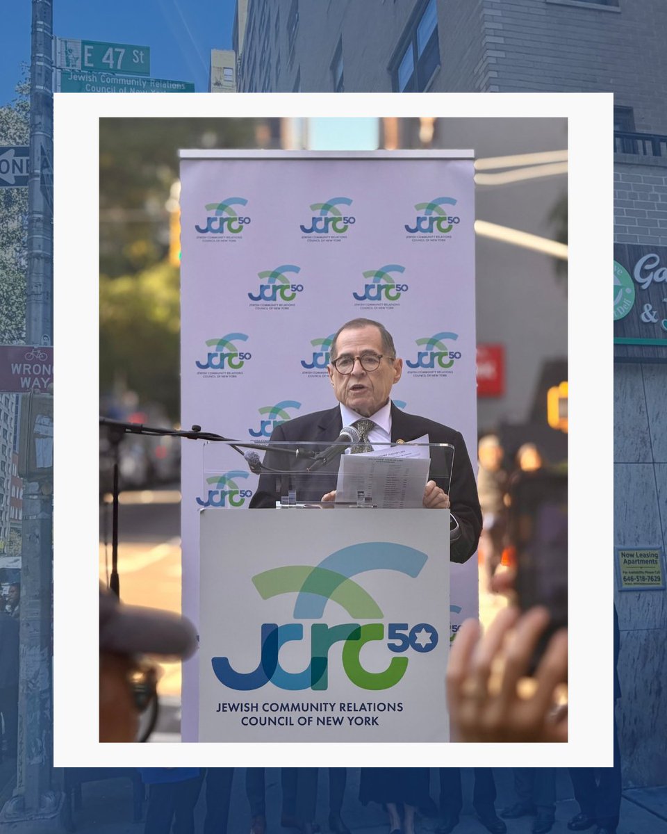 A framed photograph shows a man speaking at an outdoor podium, with microphones and papers in front of him. A branded backdrop is behind him, and a city street scene with signs and buildings surrounds the photo. Text appears throughout the image.