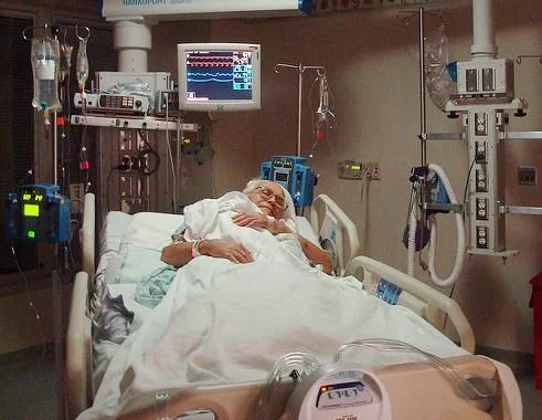Older man in hospital bed with medical equipment around him