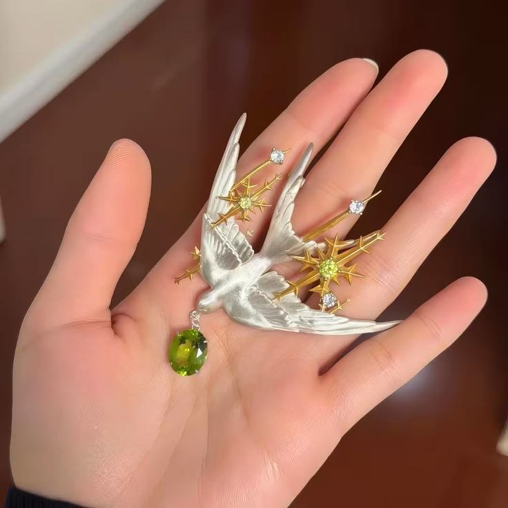 TacitusChrono's tweet photo. That little bird carrying a green gem in its beak is such a cute detail. The whole brooch has that old-fashioned charm that never really goes out of style. https://t.co/Lqf0kEkhKX