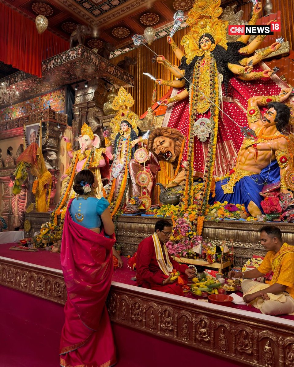 CNNnews18's tweet photo. Bollywood star Alia Bhatt attended the North Bombay Sarbojanin Durga Puja, organised by the family of her close friend and director Ayan Mukerji. The actor channelled her Rocky Aur Rani Kii Prem Kahaani character Rani Chatterjee in a red saree paired with a sky-blue puff-sleeved blouse featuring lotus and crescent moon motifs. 

She completed her festive look with a neat bun adorned with a gajra, gold jhumkas, bangles and a cocktail ring. Alia also participated in the aarti and served bhog at the pandal. Her visit came days after her husband, actor Ranbir Kapoor, who stars in Ramayana, attended the Durga Puja celebrations.

#AliaBhatt #Bollywood #DurgaPuja