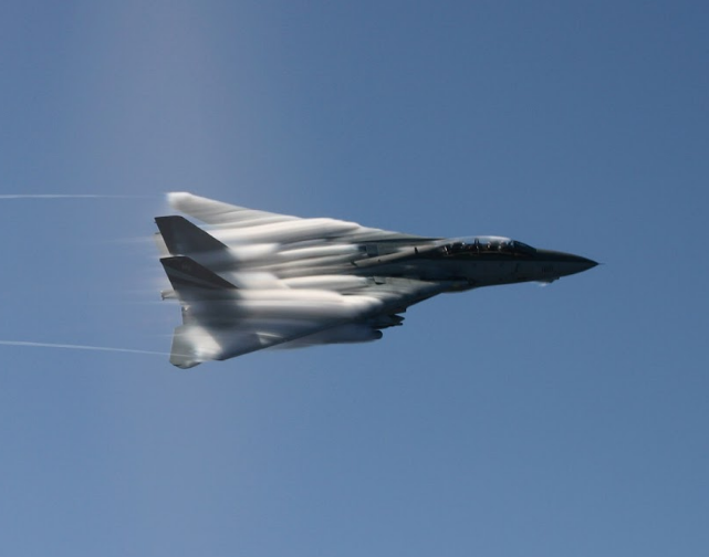 RSE_VB's tweet photo. #TomcatTails Number 87
#TomcatTuesday

“A Simple Level Turn to Downwind….Sort Of.”

“Snapper” Bull was one of my best friends and squadron mates in the VF-24 Renegades and the VF-101 Grim Reapers. He’d come to VF-24 sometime in 1994 as a former A-6 BN that had left the Intruder community as it was slowly de-commissioning squadrons.

We immediately hit it off and flew together quite a bit. He brought extensive knowledge of the Air-to-Mud mission just as the Tomcat community was ramping up that mission set. And he, like me, was a bit of a Liberty Risk in CONUS and overseas. The term “Liberty Risk” is normally used to designate Sailors that had conducted themselves in a……less than exemplary manner while on Liberty, shall we say.

So when Snapper and I went on Liberty, we’d typically have a really good time (just short of Law Enforcement being involved). And in a foreign country on Liberty it was something like this:

Corky on Liberty: “Uh oh.”
Snapper on Liberty: “Oh shit.”
Corky AND Snapper on Liberty: “Alert the consulate.”

At any rate, we flew together quite a bit and shared a similar “aggressiveness of spirit” in the jet. Nothing ever stupid, nothing ever unsafe, but if we faced a limit (speed, altitude, etc.) you’d find us snuggled up right against that limit.

We were on a cross country at one time, flying a VF-101 jet out of NAS Oceana to somewhere. One of the stops we’d filed for was some Air Force base, since AF bases typically had great turn around services. As we arrived near our destination and descended toward the Initial Point we were directed to switch to tower frequency and check in.

We were about 5 miles from the AF base descending toward 2,000 feet and the following conversation happens:

Snapper: “Tower, Rage 102 checking in, IP inbound for the overhead, request carrier break.”

Tower: “Roger that Rage 102, your cleared for the overhead. What’s the carrier break?”

<When landing at the carrier, you enter the pattern via the carrier break; 800 feet entry then 600 feet on the downwind leg to the approach turn.>

Snapper: “Tower, Rage 102, a carrier break is an 800-foot level turn to downwind.”

Tower: “Rage 102, copy that. Cleared for the carrier break.”

Snapper (to me): “It’s on tape…cleared weird dude.”

<I had already firewalled the throttles to military power as soon as the “d” sound in “cleared” was heard.>

This particular AF base, like many, was out in the boonies with miles of open land surrounding it, so I simply lowered the nose and got to about 450 knots and 800 feet a couple miles from the runway. Then I thought better of it. Breaking at 800 feet and descending to 600 feet is like two steps; kind of complicated. Maybe it’d be more safe if I just executed the break at 600 feet.

Hell, the 90° position is 450 feet. Let’s do it at 450 feet……ish. Meanwhile, Snapper has his arms on the canopy rail, just enjoying the show.

We came zorching over the runway wings back at 400 feet (ish) at about 450 knots. I took it all the way to mid field, so more people could enjoy the show… I mean be safety observers. A nice smooth parade roll left to 90° angle of bank, and lay on a punishing 6.5G pull as I went to full zone 5 on both engines, sweeping the burner cans across the entire airfield, bathing the base in the Sound of Freedom (and probably setting off all the car alarms in the parking lots).

Decelerate, speed brakes and wings out, gear down, flaps down, turn to final and land (right on the nice shiny white runway numbers to make some skid marks on them because we can). As we rolled out, tower called us:

Tower: “Rage 102, Tower.”

Snapper: “Go ahead, Tower.”

Tower: “That was……impressive. Cleared to switch ground.”

Yes, it was, Tower. Yes, it was.