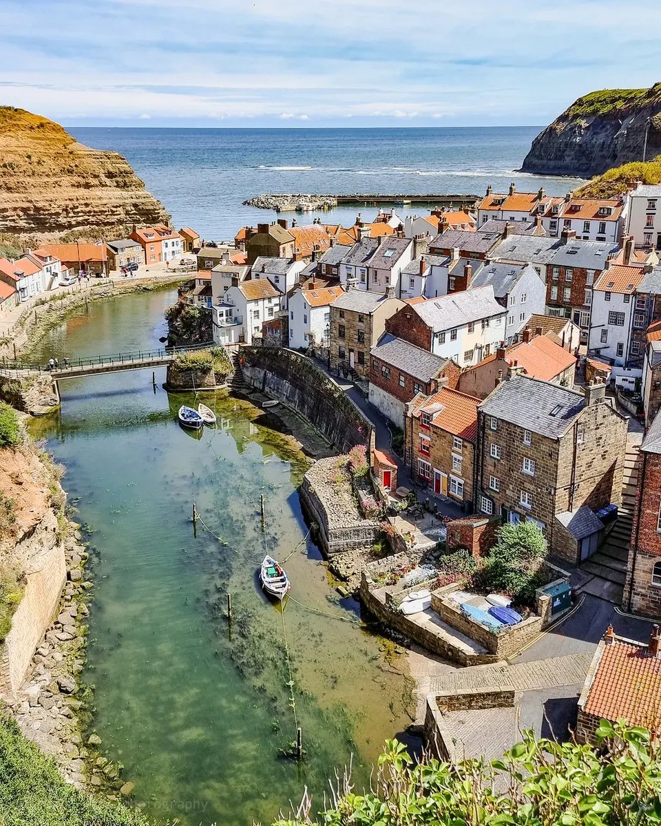 visitnorthyork's tweet photo. Fishing boats resting gently on crystal clear water, red rooftops stacked tightly together and two towering headlands sheltering the whole village from the North Sea.

With a view like this it's easy to see why Staithes has been drawing fishermen and artists alike for centuries. https://t.co/H4cJMT2daG