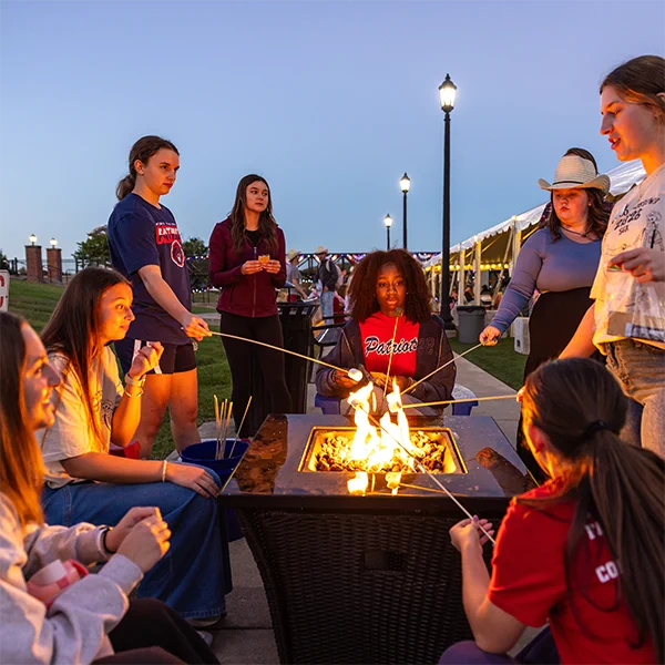 University of the Cumberlands students sit around a fire, roasting marshmallows during Hoco Hoedown on the Wellness Lawn.