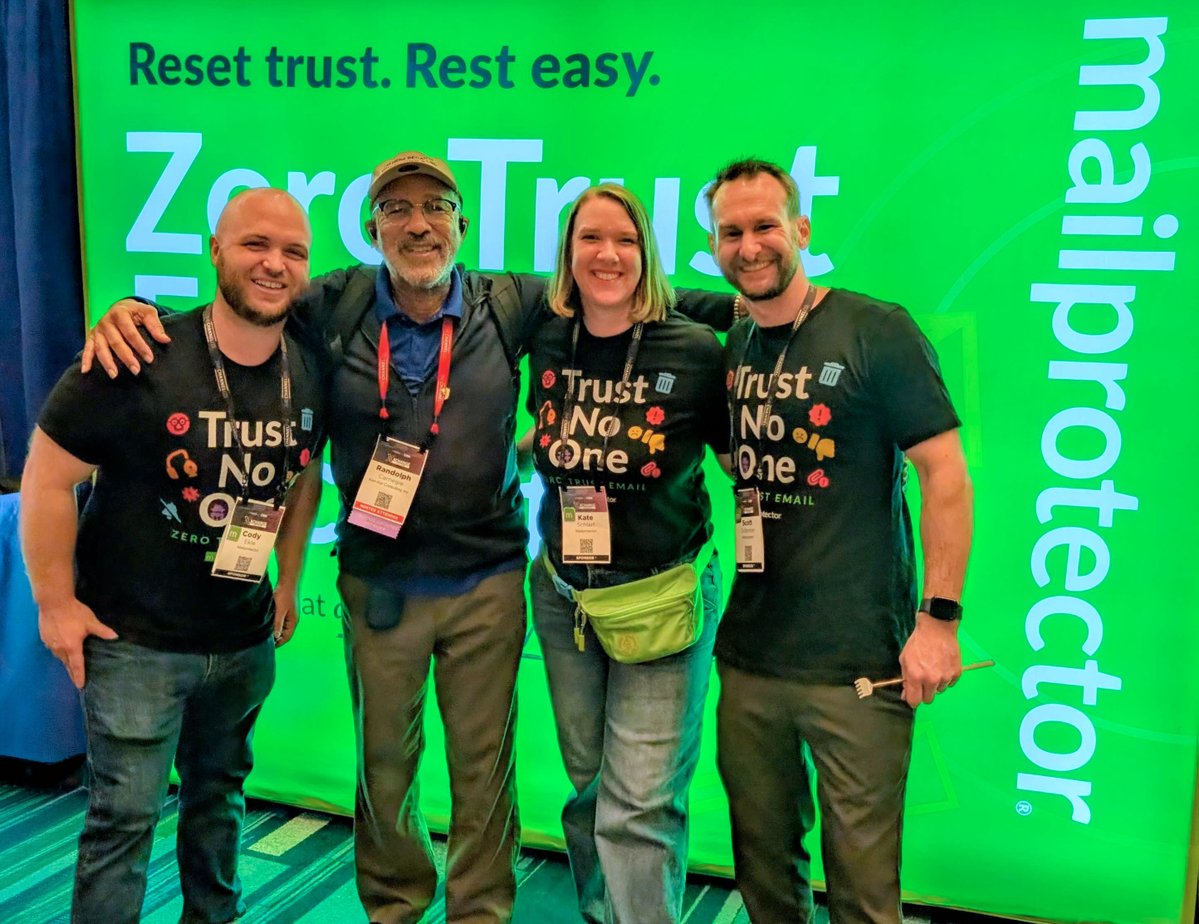 mailprotector's tweet photo. Three of us are wearing shirts that say Trust No One. Then our partner, Randolph Carnegie of Ken-Kar Consulting, walked up, and the arms went around shoulders anyway. He knows how much zero trust matters for email. Cody, Kate and Scott are at NexGen, booth 101. https://t.co/PAjqcujfxb