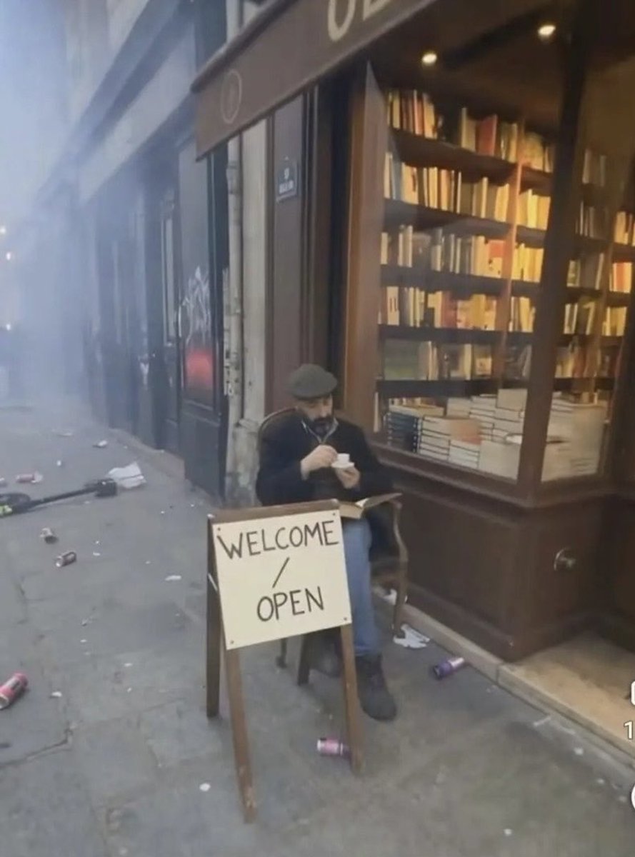 PatColon's tweet photo. Durante las protestas de los “estudiantes” en Francia, un librero se sienta frente a su tienda intacta.

Una imagen extraordinaria.

Esta fotografía pasará a los libros de historia. https://t.co/2G9uEAvUeD