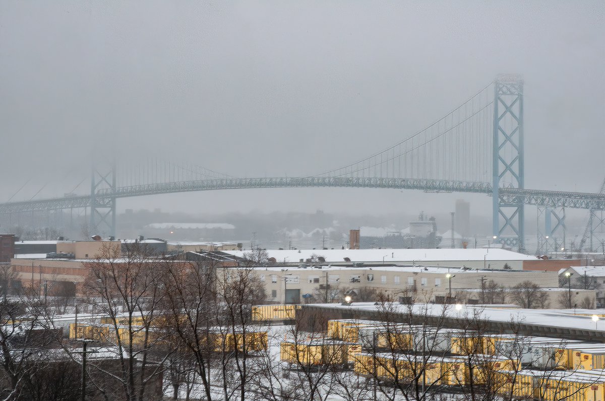 ExploresMr's tweet photo. A snowy view of Detroit, Michigan's Ambassador Bridge from a gutted and gargantuan cold storage building, circa 2020. This building has since been commandeered and is being turned into apartments and businesses. At the time, it was completely empty and without windows. https://t.co/5eQ0G9JEBM