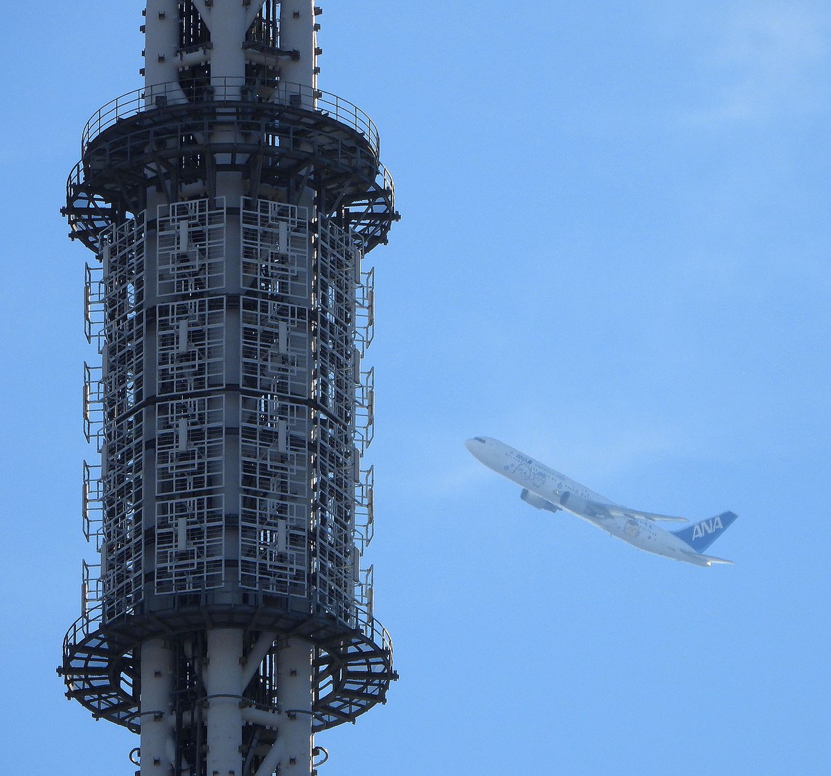 tetsu_skytree's tweet photo. 2026/10/22、8:56、荒川上空を飛ぶ スカイツリー越しの ANA ちいかわジェット。羽田→長崎行き。浅草から撮影。この時間帯は逆光なのでピントが難しい。
#JA609A https://t.co/gIsXhRO4wV