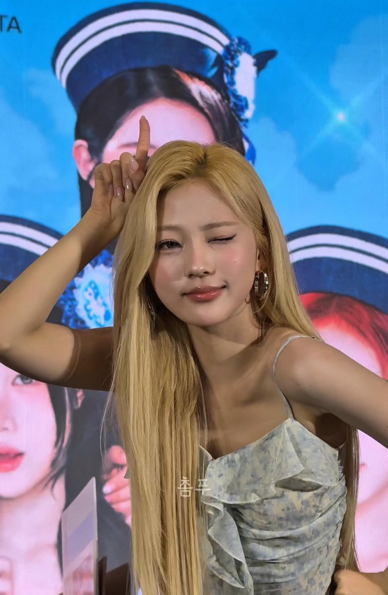 Rosé from BLACKPINK poses on a bright blue stage backdrop, winking and raising one finger, with Korean text “체크” over her outfit.