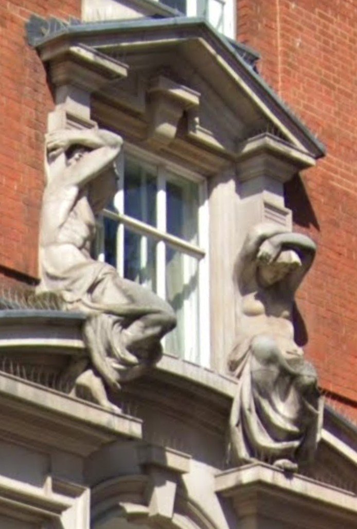 Knowledgepoint's tweet photo. "Atlantes Holding Up Fresh Air" (82 Mortimer Street): 

One of the most eccentric architectural details,  designed by the highly individualistic Arts and Crafts architect Arthur Beresford Pite in 1896, the building's facade features a striking window treatment. 

Flanking a prominent upper-level window arch, you will find deeply expressive, Michelangelesque stone sculptures of an Atlante (male figure) and a Caryatid (female figure). Because of how the window frame is recessed, they humorously look as though they are straining to hold up nothing but empty air.