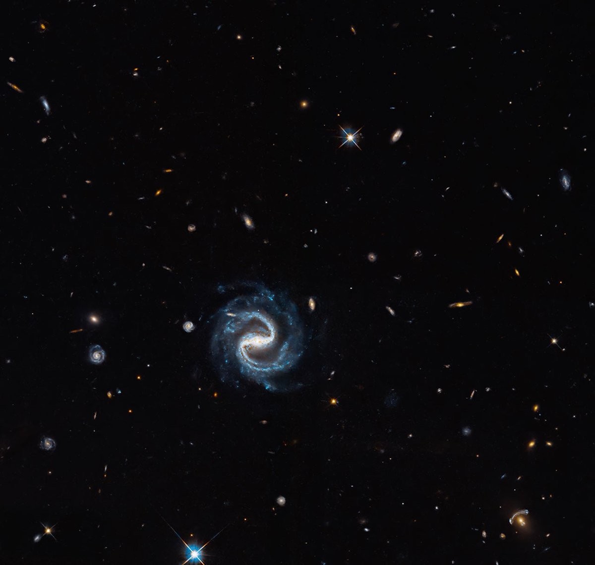 NASAHubble's tweet photo. A gorgeous galaxy marks the spot in this image, but the real treasure is the gravitational lens in the lower-right corner, where a distant background galaxy is being magnified and distorted by the gravity of a closer galaxy: https://t.co/Y5Y3v8pxl4 https://t.co/Z3rQihoMoq