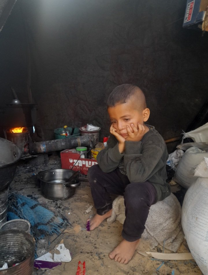 anas___1990's tweet photo. This is how we live in Gaza under the weight of genocide and displacement. Children have been deprived of their most basic rights, living inside a tent surrounded by dirt and fire instead of the warmth of a home and the safety of childhood.
My children do not dream of toys or a luxurious life, but simply of a meal to satisfy their hunger, a home to protect them, and days when they no longer have to fear tomorrow. 
 Help carry the voices of Gaza’s children to the world. Perhaps your words can help bring support to my family and others suffering through this hardship.
https://t.co/juhZUvafMS