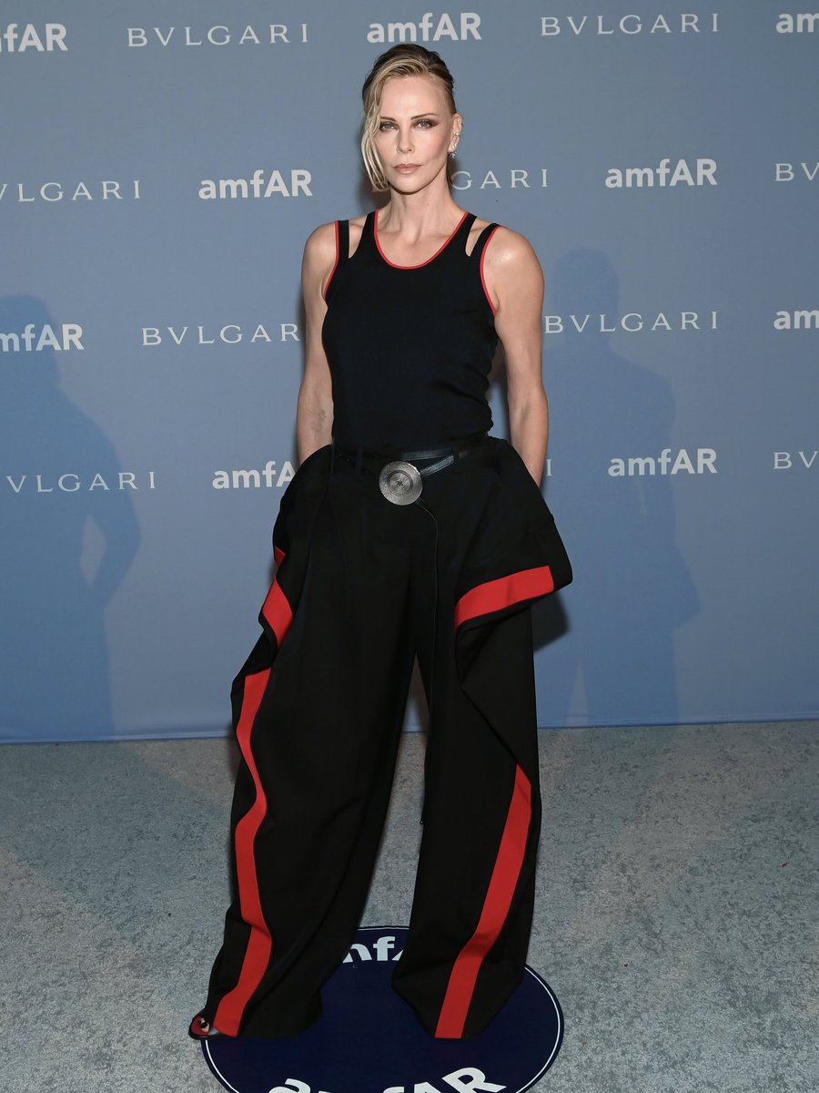 givenchy's tweet photo. Charlize Theron, honoured with the Award of Inspiration, wore a black knitted sliced vest and wool pattern-piece trousers with the powder puff jewellery belt and Mobile zipped mules to amfAR Dallas 2026.

Givenchy by Sarah Burton https://t.co/Jym81luxDs