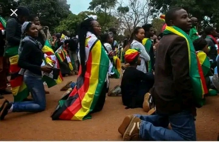 TakudzwaChiwade's tweet photo. Look at us. Kneeling, flag on our backs. This is love for Zimbabwe.  
But love means telling the truth: we suffered. We buried people. We lost homes. We were scattered across the world because of bad governance.  
Now they want CAB2/CAB3 to stay longer in power?  
NO. We want change. We want the Constitution respected. We want a Zimbabwe where no one else has to leave their home to survive.  
*#NoToCAB #ZimbabweDeservesBetter* 🇿🇼