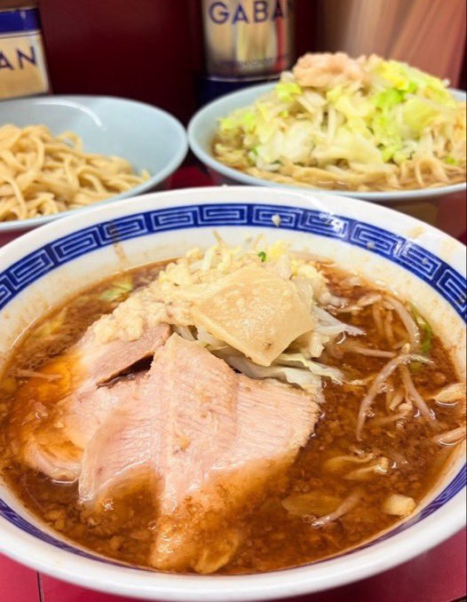 delicious2626's tweet photo. 昨日のラーメン二郎 中山駅前店
昨日は小滝×2→中山×2で4杯着地
昨日で1200日連続でラーメン二郎を喰ったことになる(3年3ヶ月ちょい

同時に1128日連続で1日最低でも2杯以上ずつは喰っとることとなる
ラーメンとぶったまつけ麺の2杯同時喰い
メガネさん麺あげ
2杯ともめちゃくちゃ旨かった!

まずお久しぶりのぶったまつけ麺

マー油由来の芳醇な香ばしさが実に好みで、個人的には中山における歴代つけ麺メニューの中でも最上位に君臨する逸品
また、これまで摂取してきた「〇〇たま」の名称を冠する各種メニューと比較しても、玉ねぎの存在感が最も顕著
醤油感も過度な塩味を伴わず、絶妙なバランス
つけ麺だが麺も必要以上に硬くなく
後半のスープ割りを施行後も、危うく飲み干しかねないほどの危険な旨さだった

なお注文内容は両者とも麺量据え置き、コールはニンニクアブラ

有料トッピングについては生卵及びピリ辛きくらげに限定し、日本国の法定通貨たる日本円を対価として自動券売機を介した売買契約を経営側と締結することにより、適法かつ平穏にその所有権を取得した
(訳:生卵とピリ辛きくらげの食券を買った

一方のラーメンも、鋭利な醤油感と豚由来の旨味が高次元で共存していた
しょっぱくはないがでもキリッと鋭利という素晴らしさ

麺は柔らかめ指定を行っていないにもかかわらず、モチッとした弾力とクニュっとした柔和な食感を兼備しており、こちらも好み

豚はいずれの丼においても高水準で、今回は中山基準では比較的脂身の含有率が高い個体が中心
脂身大好きマンとして名を馳せている(馳せてない)小職にとっては、まさしく嗜好の核心を突く構成であり、右事情に照らせば満足度が著しく高かったことは論を俟たない

ヤサイはキャベツ含有率がドチャクソ高く、これもまた旨かった
最近、クタかシャキかといった食感上の分類よりも、キャベツ率の高さこそがヤサイの評価を大きく左右するという考えを一層強固にしてる(個人的見解

ニンニク及びアブラについては性欲を抑えきれずに挿入
アブラは味染みのない大ぶりな個体がヤサイの山の頂点に設営

ピリ辛きくらげは想像より甘味を内包しながら、名称どおり適度な辛味も兼備しており旨い

なお、うずら及び甘〜い脂の追加購入については、1126無量大数1919不可思議3150那由他0039億4649万回に及ぶ葛藤を経た結果、断腸の思いで購入を見送った
右決定については、既に2杯同時喰い×2を敢行している事情を斟酌すれば、一定の合理性を有するものと解するのが相当である(訳:デブだから我慢した

食事終盤には隣席の方から「2杯すごいですね。YouTubeとかやってるんですか？」と声掛けいただいたうえ、今後視聴したいので名称を教えてほしいとのありがたいお言葉まで頂戴

大変光栄である一方、改めて第三者に口頭で伝える際には若干の羞恥心を伴うチャンネル名であることを再認識w

店内では中山ご店主さんのお父様を久方ぶりに観測したものの、ご店主さんご本人は不在🥹

到達時には、
15名の医療情報基盤診療報酬審査支払機構構成員が雁首揃えて跋扈していたが、驚異的な光の速さの回転率により待機時間は大幅に控除され、瞬く間に着席
感謝！

食後は音速で拙宅へ帰還し、夜は酒ちゃんと飲みに闊歩
飲酒と並行して動画投稿まで完遂するという、自称YouTuberの鑑

酒席が想定以上の盛り上がりを見せた結果、「VIVANT」の放送開始時刻に間に合わない事態が現実味を帯びたものの、
野球中継の延長に伴う放送時刻の繰下げという予期せぬ救済措置が発動し、辛うじて視聴権を確保

野球のルールがほぼわからないほど野球に関しては無知の極み乙女だが、助かった

その後はメンシプ配信を敢行
存外に盛り上がって23時から26時半まで3時間半実施
メンシプメンバーにはいつも感謝

誠に良い1日でした