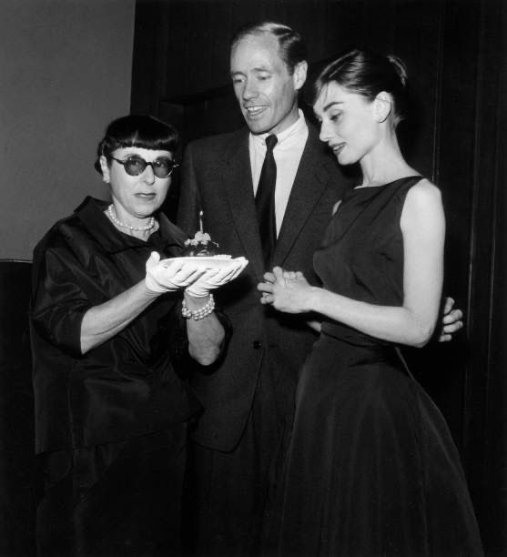 CitizenScreen's tweet photo. Edith Head holds a cupcake with a lighted candle to celebrate her birthday as Mel Ferrer and Audrey Hepburn look on, at a Don Hartman party for Ferrer and Hepburn at the Beverly Hills Hotel, circa 1953. https://t.co/9GMnJOMsd8