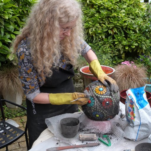Artist working with mosaics and glass to produce colourful birds, wall hangings and jewellery