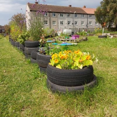 An outdoor community growing fresh food in an urban garden, selling plants, drinking tea and eating cake together