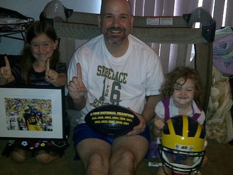 My girls and me with my most prized possesions! My oldest has my autographed Denard Pic from the ohio win in 2011!! My youngest has my helmet. Go Blue! #HailJim