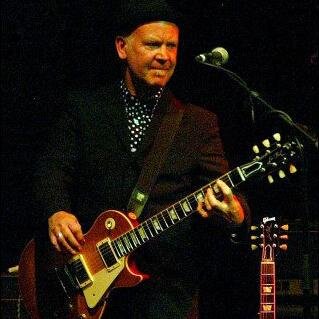 Plays a Les Paul, sings a bit and wears a hat!
