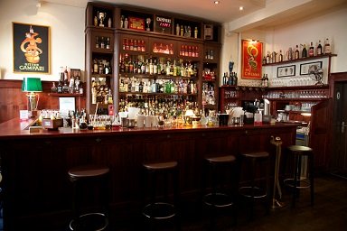 NegroniClub's profile picture. The Mauro's Negroni Club, where guests can relax and enjoy wood-paneled walls, dark furniture, which makes a good contrast to the bright walls with wall lights.