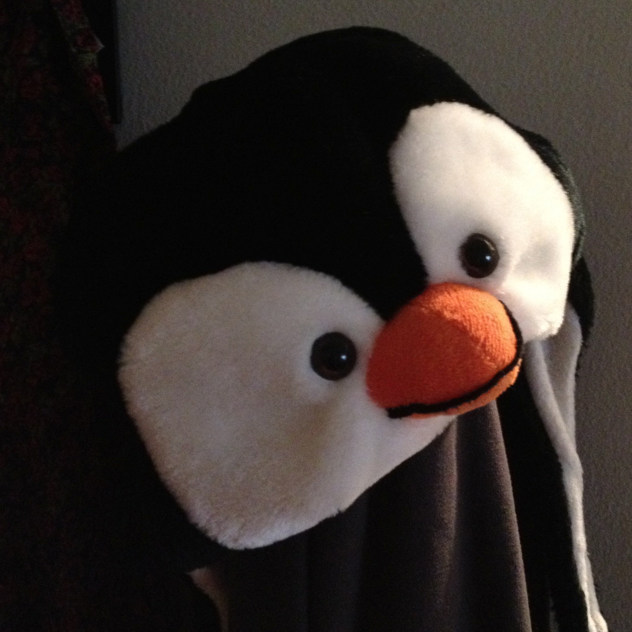 A penguin hat on a coat rack.