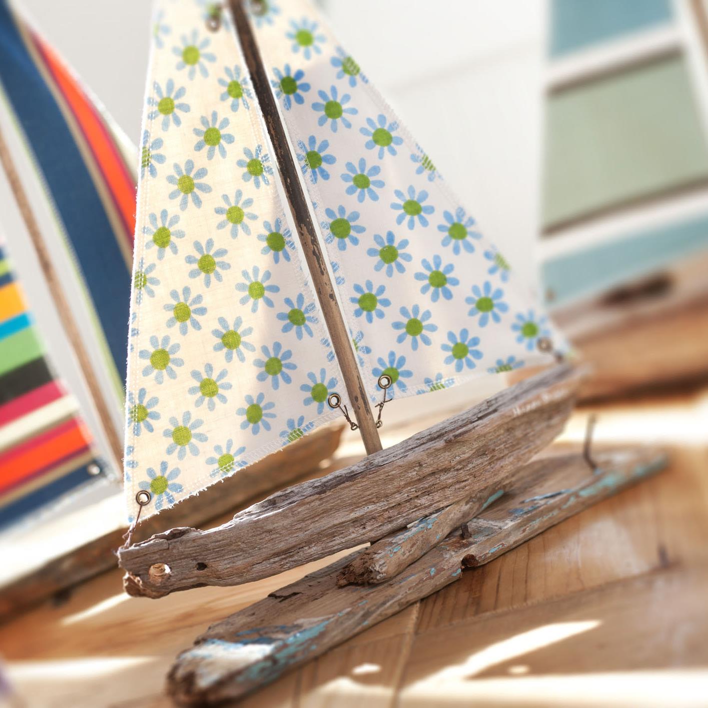 designs and hand-makes driftwood boats and boat sculptures adorned with striped fabric sails