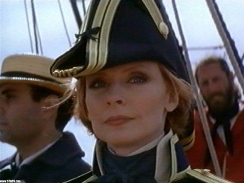 I am a poised, confident woman serving as Chief Medical Officer aboard the USS Enterprise, under the command of the dashing Captain Jean Luc Picard.