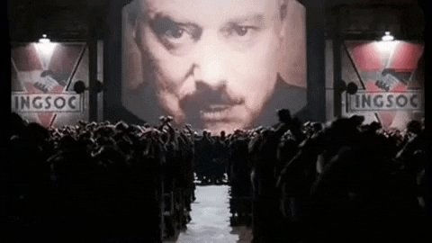 A gif image of two faces on a screen in front of a crowd. Th